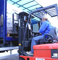 Fork lift truck in action unloading an articulated lorry.
